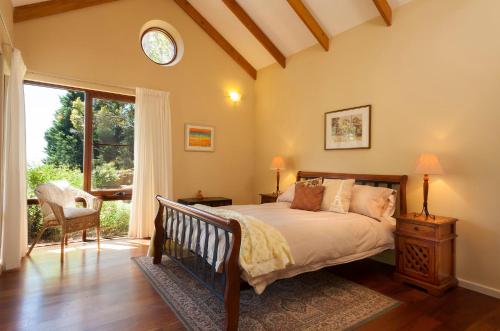 a bedroom with a bed and a large window at Innisfree Mountain Retreat in Denmark