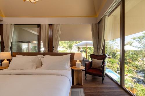 a bedroom with a large bed and a chair at J Valley Resort in Pong Yaeng