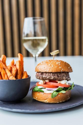 a plate with a hamburger and fries and a glass of wine at PARKROYAL Parramatta in Sydney