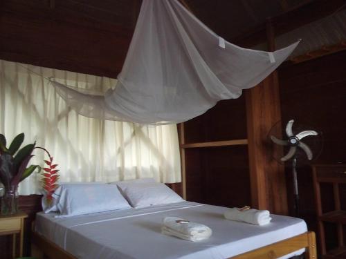 a bed with white sheets and towels on it at Tambopata River in Puerto Maldonado