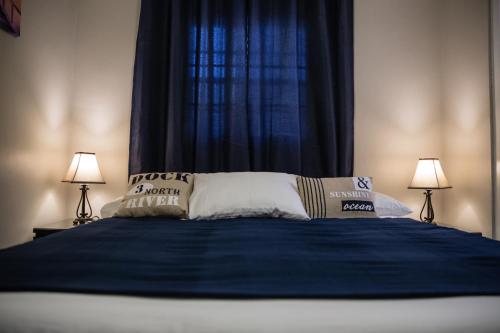 a bedroom with a bed with blue sheets and two lamps at The Pier Beach Inn & Suites in Willemstad