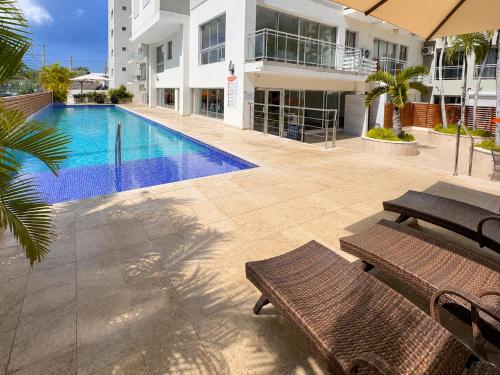 a swimming pool in front of a building with benches at Luxurious Ocean View Penthouse in Boca Chica