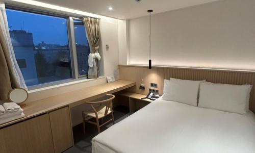 a bedroom with a bed and a desk and a window at Pohang Daejamdong Route 422 in Pohang