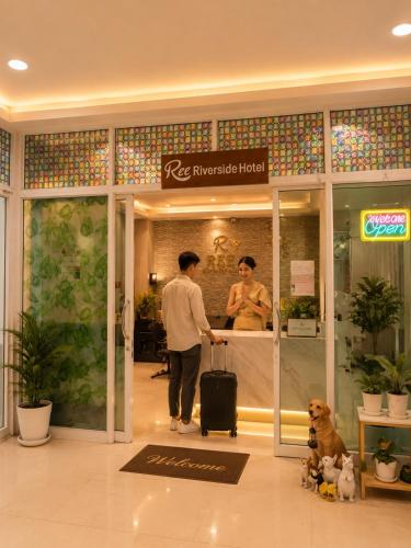 a man with a suitcase in front of a store at Ree- Riverside hotel in Bangkok