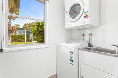 a white laundry room with a washing machine and a window at Rosslyn Bay Resort Yeppoon in Yeppoon