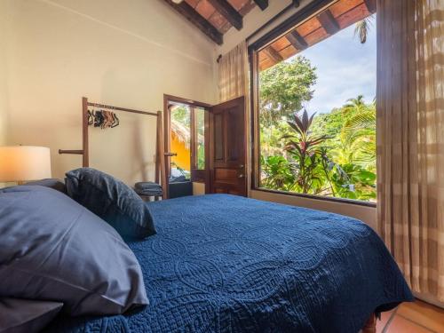 a bedroom with a blue bed and a large window at Amare Las Villas in Sayulita