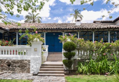 a house with a blue door and some flowers at Hotel Boutique Casa de Hacienda Su Merced in Puembo