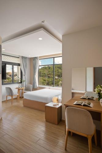 a hotel room with a bed and a desk with a desk at Gold View Boutique Hotel Đà Lạt in Da Lat