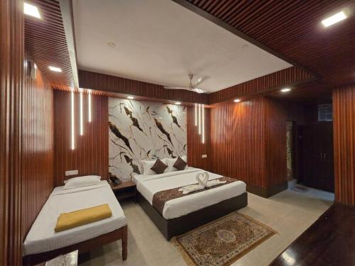 a bedroom with two beds and a wall with a painting at Hotel The King's in Port Blair