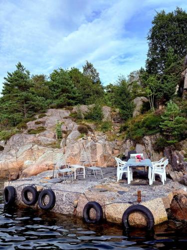 a table and chairs sitting on a rock near the water at Architect-Designed House With Pier In Ny Hellesund in Søgne