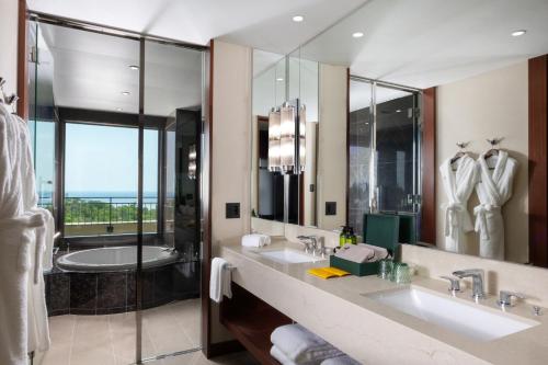 a bathroom with two sinks and a large mirror at PGM Hotel Resort Okinawa in Onna