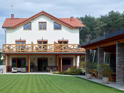 a large white house with a deck on top of a yard at Lipowa Przystań in Tarnów Jezierny