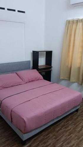 a pink bed in a room with a window at Rembulan Guesthouse in Mersing