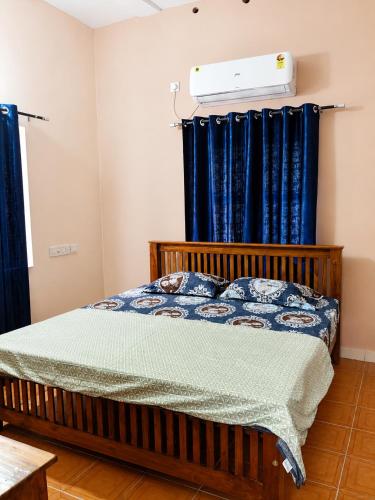 a bedroom with a bed with blue curtains at Devaki Tourist Home in Ambalapulai