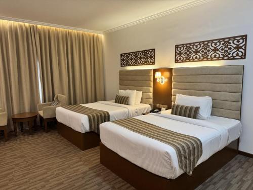 a hotel room with two beds and a desk at Hamdan Plaza Hotel Salalah, an HTG Hotel in Salalah