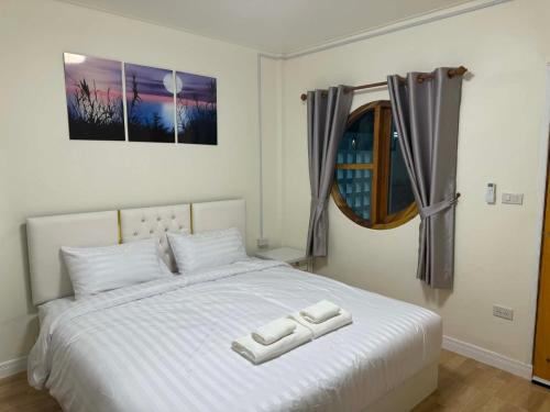 a bedroom with a white bed with two towels on it at Kasalong stay in Ban Nong Chaeng