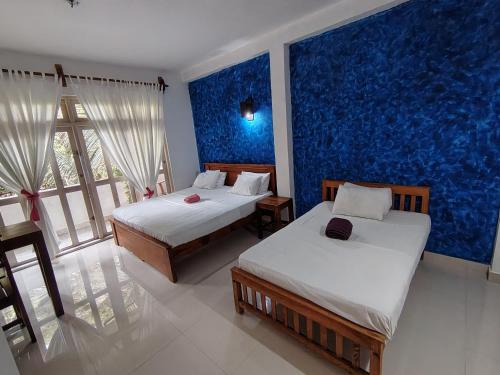 a bedroom with two beds and a blue wall at Sithila Villa in Mount Lavinia