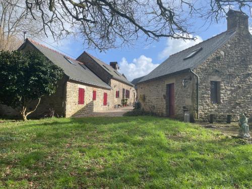 an old stone house with red doors and a yard at Le Breizh des Bois in Le Faouët