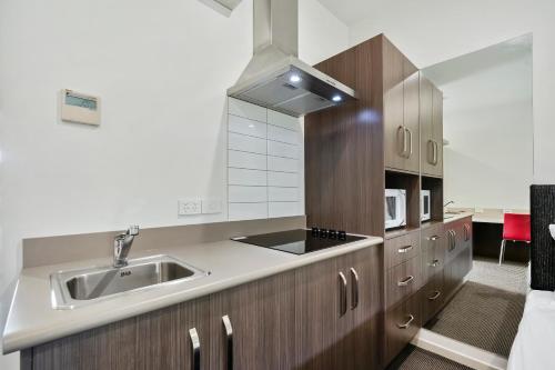 a kitchen with a sink and wooden cabinets at Quality Resort Parkhurst in Rockhampton