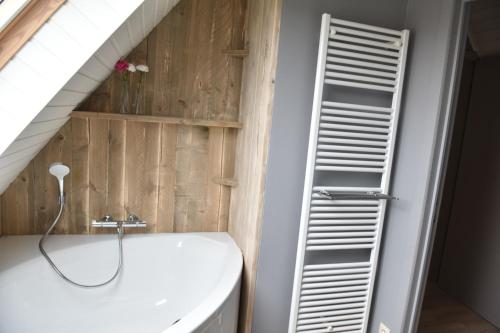 een badkamer met een ladder naast een wit bad bij Hof Ter Meulen in De Haan