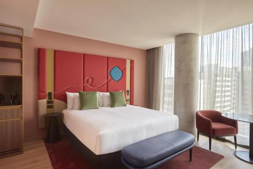 a bedroom with a large white bed and a chair at Quincy Hotel Melbourne in Melbourne