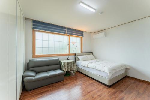 a bedroom with a bed and a couch and a window at U&I Pension in Yangyang