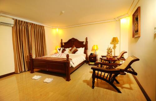 a bedroom with a bed and a table and chairs at Union Square Hotel in Yangon