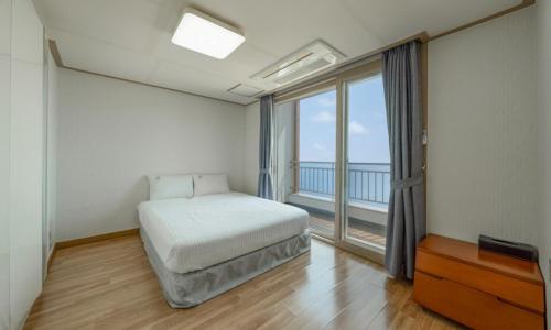 a bedroom with a bed and a large window at Mud Beach Hotel in Boryeong