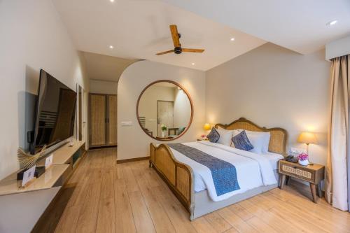 a bedroom with a large bed and a mirror at Goan Bliss Alaya Stays by ELIVAAS in Varca