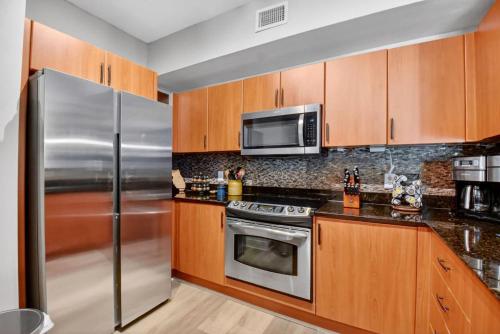 a kitchen with wooden cabinets and a stainless steel refrigerator at Moorings Pool Overview Resort in Lantana