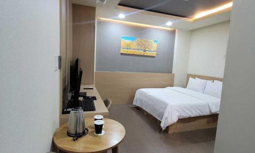 a hotel room with a bed and a desk with a television at Namyangju Benikea JD Hotel in Namyangju