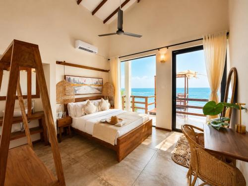 a bedroom with a bed and a balcony with the ocean at Ocean Bliss by Sugar Coliving in Weligama