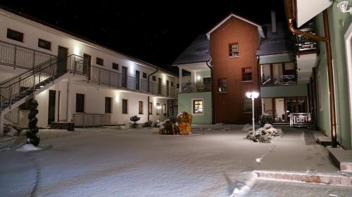a snow covered street at night with buildings and a fire hydrant at Penzión Tri Koruny in Spišská Stará Ves