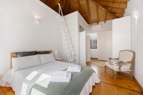 a white bedroom with a bed and a chair at Casa Miclá in Lagos
