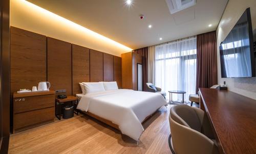 a bedroom with a large white bed and a desk at Uiwang Milos Hotel in Uiwang