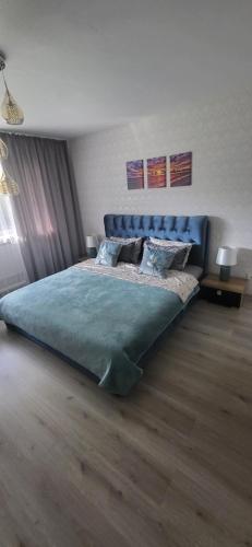 a bedroom with a large bed with a blue headboard at Apartamentai AGNIJA in Kretinga