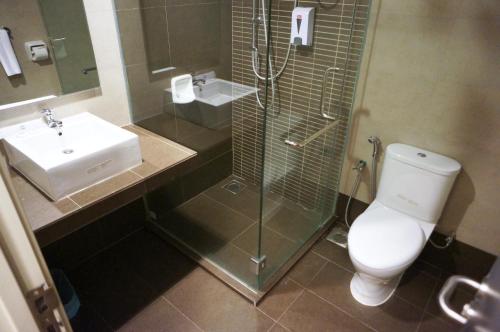 a bathroom with a shower and a toilet and a sink at Kosma Business Hotel in Kuantan
