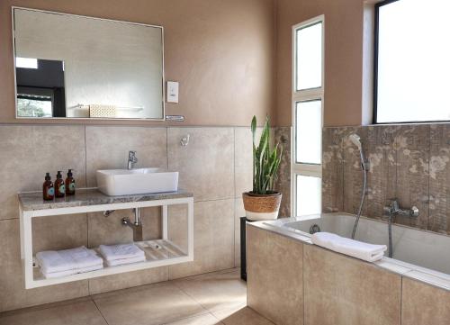 a bathroom with a tub and a sink and a mirror at Symponia Guesthouse in Khanzi