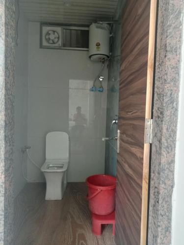 a bathroom with a toilet and a red bucket at Hotel Shankar Place in Khātu