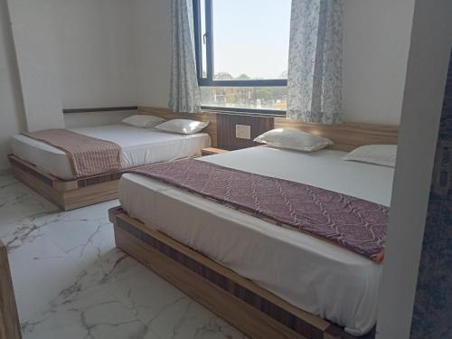 two beds in a room with a window at Hotel Shankar Place in Khātu