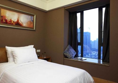 a bedroom with a white bed and a window at Dan Executive Apartment Guangzhou Zhujiang New Town in Guangzhou