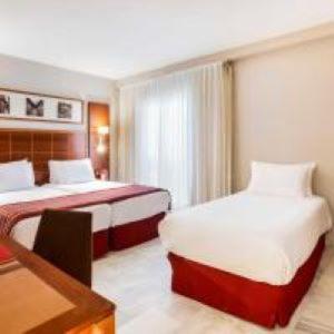 a hotel room with two beds and a table at Exe Las Adelfas in Córdoba
