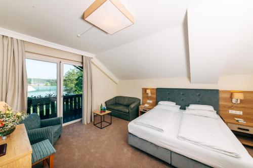 a hotel room with a bed and a balcony at Inselhotel Faakersee in Faak am See