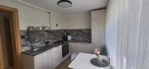a kitchen with a sink and a table with a vase of flowers at Apartamentai AGNIJA in Kretinga