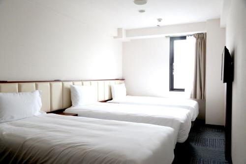 two beds in a hotel room with a window at Asia Hotel Narita in Narita