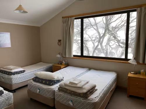 two beds in a room with a window at Illabunda Ski Lodge in Perisher Valley