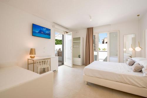 a white bedroom with a bed and a desk with a desk at Il Moro Camere&Relax in San Vito lo Capo
