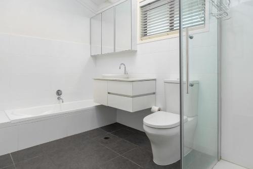 a white bathroom with a toilet and a sink at Sandpiper 21 in Smiths Lake