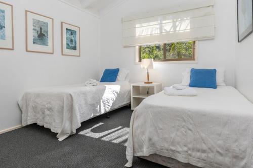 two beds in a white room with a window at Sandpiper 21 in Smiths Lake