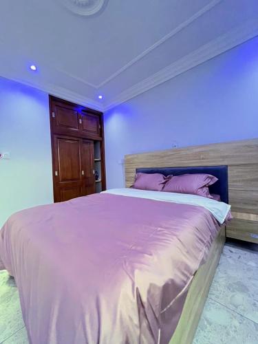 a bedroom with a large bed with purple walls at Egel appartement in Yaoundé